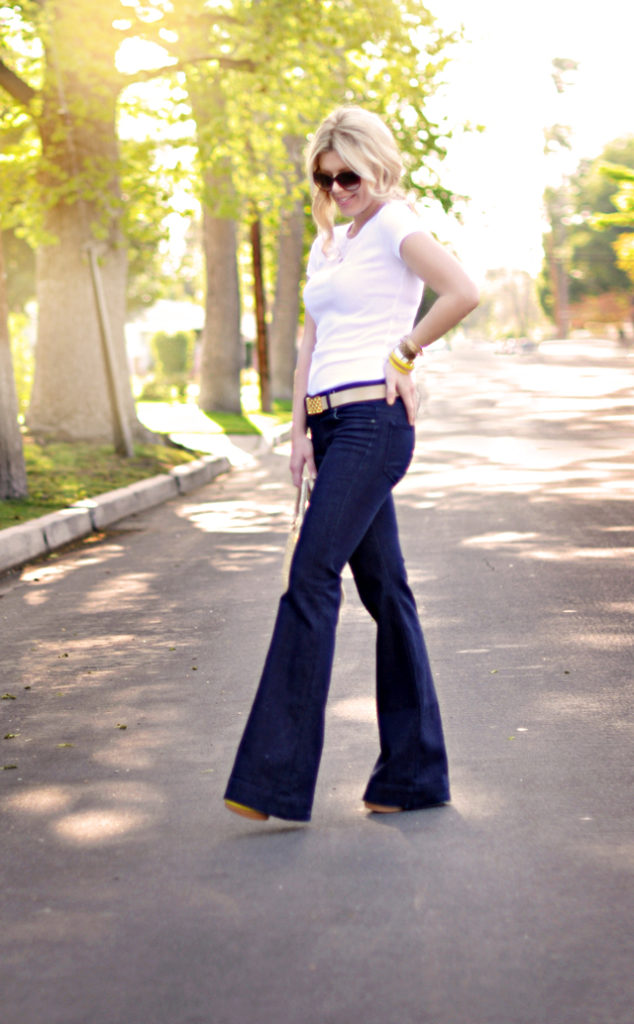 a woman in blue flared jeans and white top